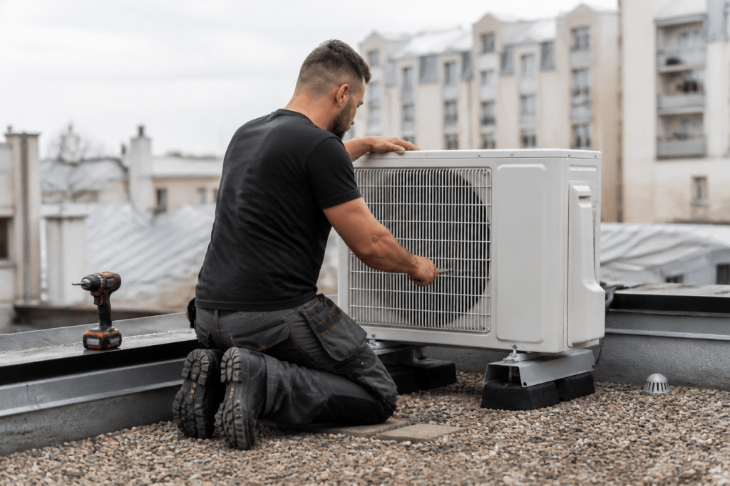 Technicien installant unite exterieure climatisation sur toiture