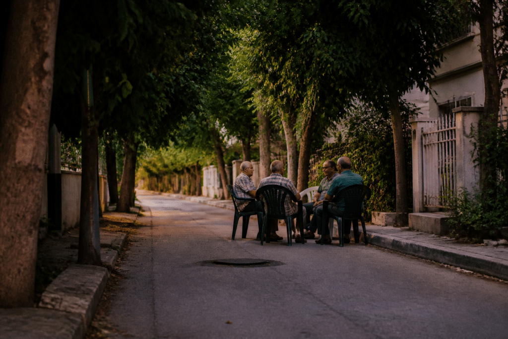 Rue paisible avec arbres verts et habitants discutant le soir