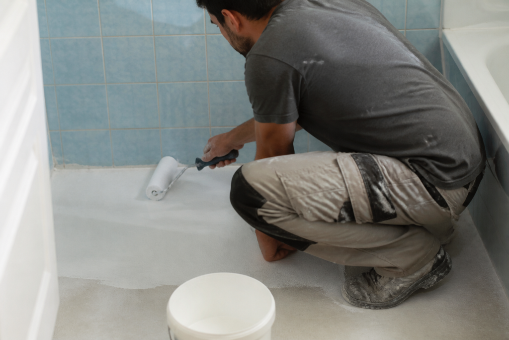 Artisan appliquant primaire sur ancien carrelage salle bain