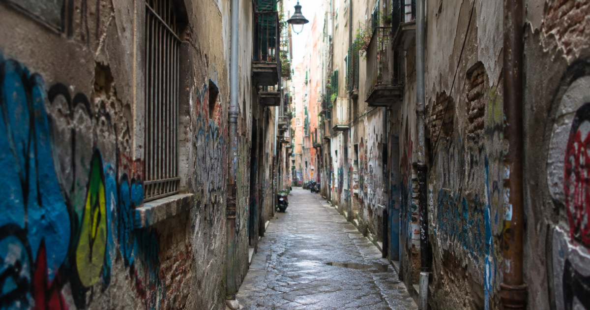 Rue etroite avec immeubles decrepits et graffitis abondants